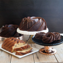 Four Heritage bundt cakes in different sizes: chocolate 10-cup and 6-cup bundts, mini bundtletts, and vanilla loaf with nuts