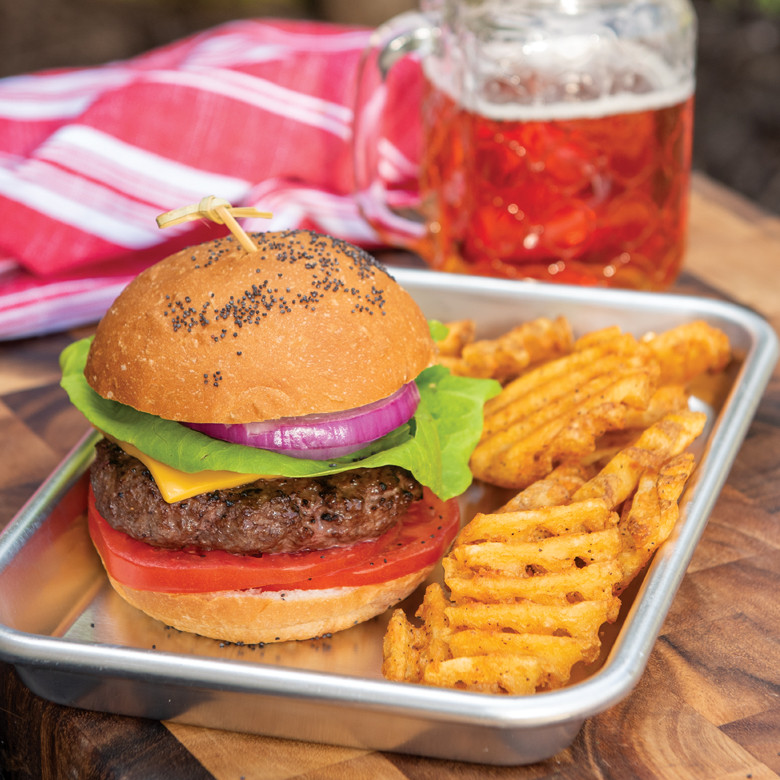 Nordic Ware aluminum burger serving tray with grilled hamburger, lettuce, onion, tomato and waffle fries
