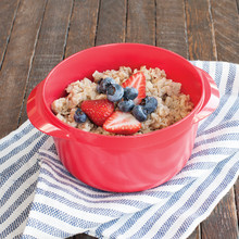 Nordic Ware red microwave multi boiler bowl with cooked oatmeal, fresh strawberries and blueberries