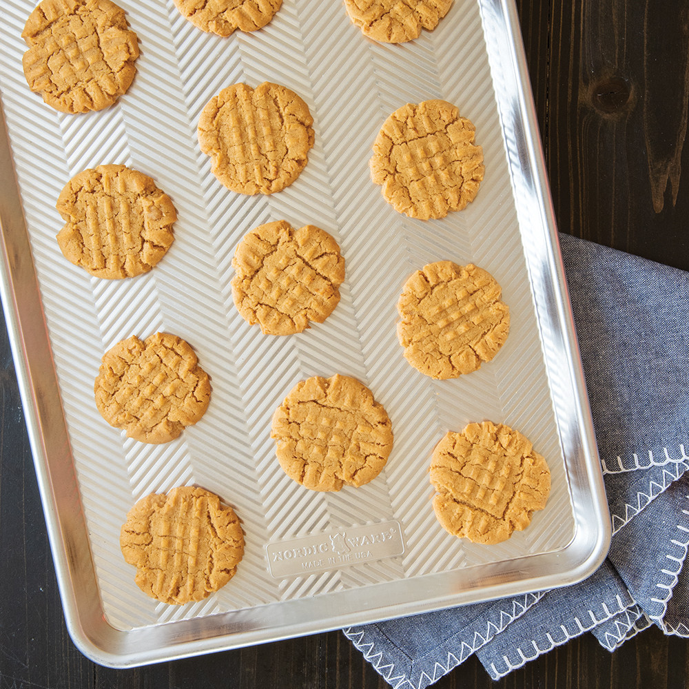 Golden peanut butter cookies with crosshatch pattern on Nordic Ware Prism aluminum half sheet pan