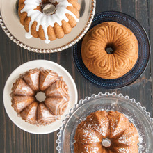 Four golden bundt cakes from Nordic Ware Quartet pan, each with different toppings: glazed, plain, powdered sugar, chocolate