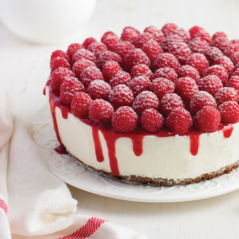 White cheesecake topped with fresh raspberries and red berry drizzle, baked in Nordic Ware springform pan