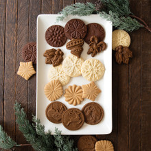 Assorted holiday cookies with Nordic Ware Yuletide stamp impressions on white platter, golden and brown colors