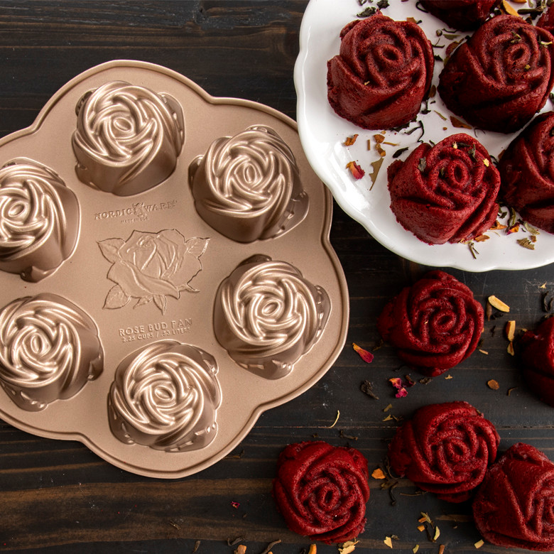 Nordic Ware bronze aluminum rosebud cake pan with six rose-shaped cavities alongside red velvet rose cakes