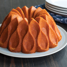Golden vanilla bundt cake with Nordic Ware Crown pan's distinctive swirled ridges on white serving plate
