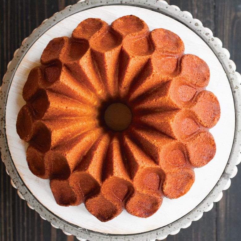 Golden vanilla bundt cake baked in Nordic Ware Crown bundt pan showing distinctive petal design on white plate