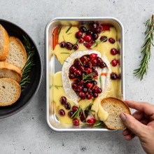 Baked brie with cranberries and herbs on Nordic Ware aluminum eighth sheet pan, golden cheese melting