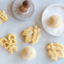 Nordic Ware cookie stamp with cut maple leaf and flower-shaped dough pieces, sugar-coated dough balls
