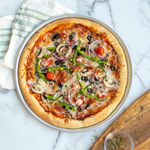 Baked vegetable pizza with olives, peppers, and red onions in Nordic Ware aluminum pizza pan with golden crust