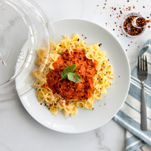 Clear Nordic Ware deluxe plate cover over white plate with spaghetti and red sauce, garnished with basil