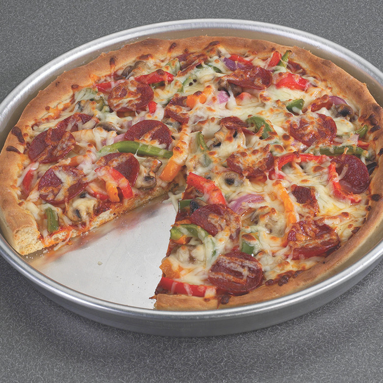 Deep dish pizza with vegetables and cheese baked in Nordic Ware aluminum pizza pan, one slice removed