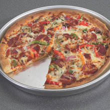 Deep dish pizza with vegetables and cheese baked in Nordic Ware aluminum pizza pan, one slice removed