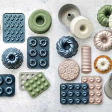 Nordic Ware aluminum baking pans collection including bundt pans, muffin tins, and specialty molds in various colors