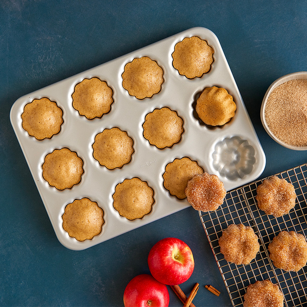 Nordic Ware aluminum mini bundt cupcake pan with golden baked cupcakes, cooling rack with additional cupcakes