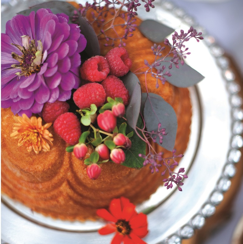 Chocolate bundt cake in Nordic Ware Chiffon pan, garnished with purple flowers, raspberries, and herbs