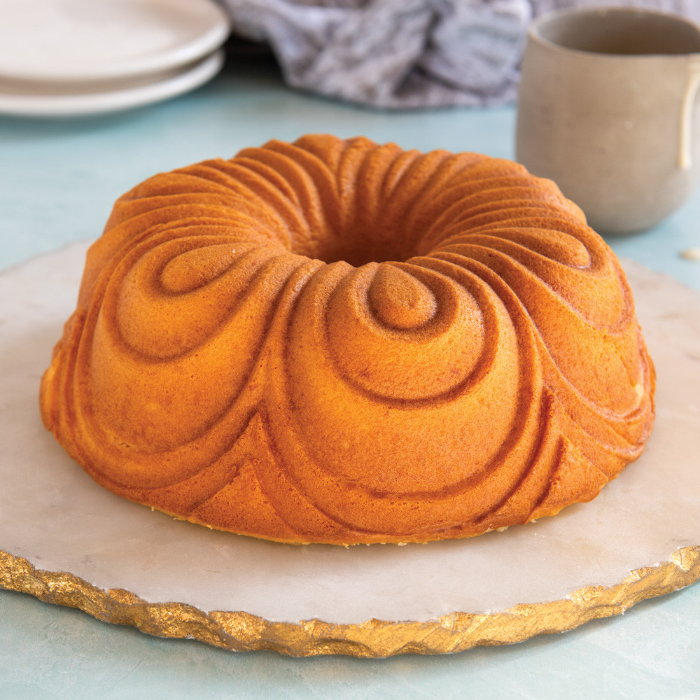 Golden chiffon bundt cake from Nordic Ware pan, showing elegant swirled pattern design on white plate