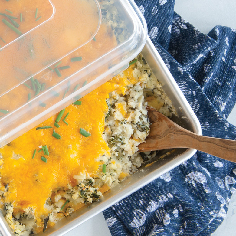 Nordic Ware aluminum rectangular baking pan with clear lid containing golden baked casserole with herbs