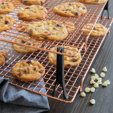 Freshly baked chocolate chip cookies cooling on Nordic Ware copper-colored stackable wire cooling grids