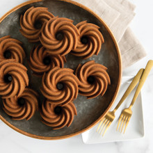 Golden spice cakes baked in Nordic Ware Heritage Bundtlette pan, swirled fluted design, arranged on dark plate
