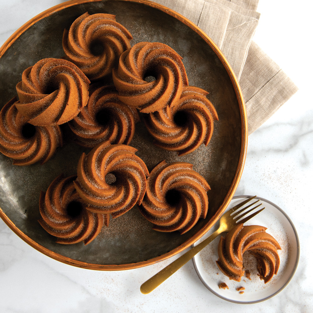 Golden spice cakes baked in Nordic Ware Heritage Bundtlette pan, swirled fluted design, arranged on dark plate