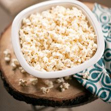 Nordic Ware white microwave popcorn popper filled with fluffy popped kernels, overhead view on wooden surface