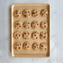 Sixteen golden chocolate chip cookies arranged in rows on Nordic Ware nonstick big sheet baking pan