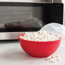 Nordic Ware red Quick Pop microwave popcorn bowl filled with fluffy white popped kernels
