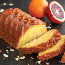 Golden blood orange loaf cake baked in Nordic Ware Jubilee pan, sliced to show moist interior, oranges nearby