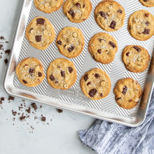 Freshly baked chocolate chip cookies on Nordic Ware Prism aluminum big sheet pan with textured surface