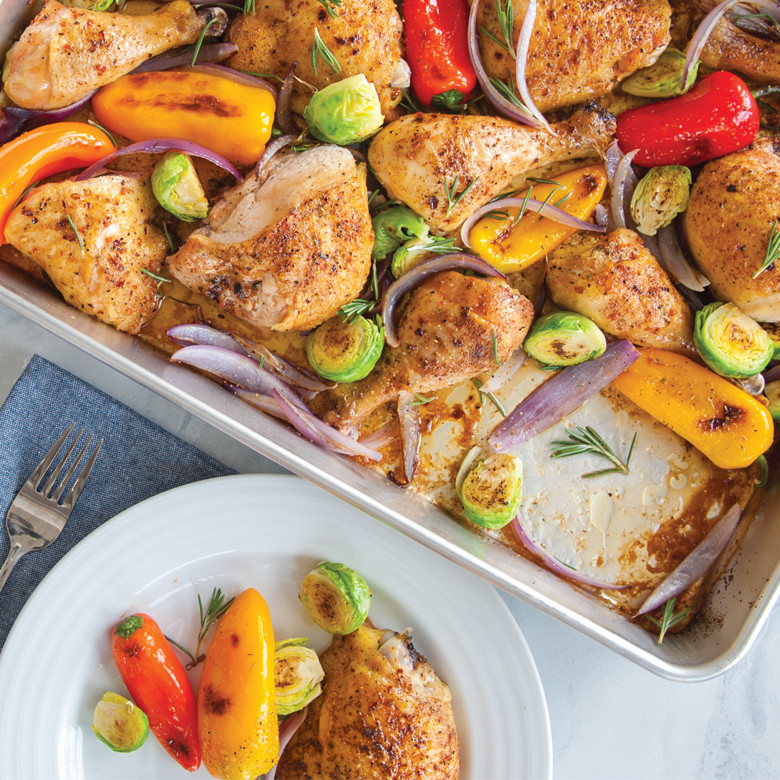 Golden roasted chicken thighs with colorful bell peppers and Brussels sprouts in Nordic Ware aluminum sheet pan