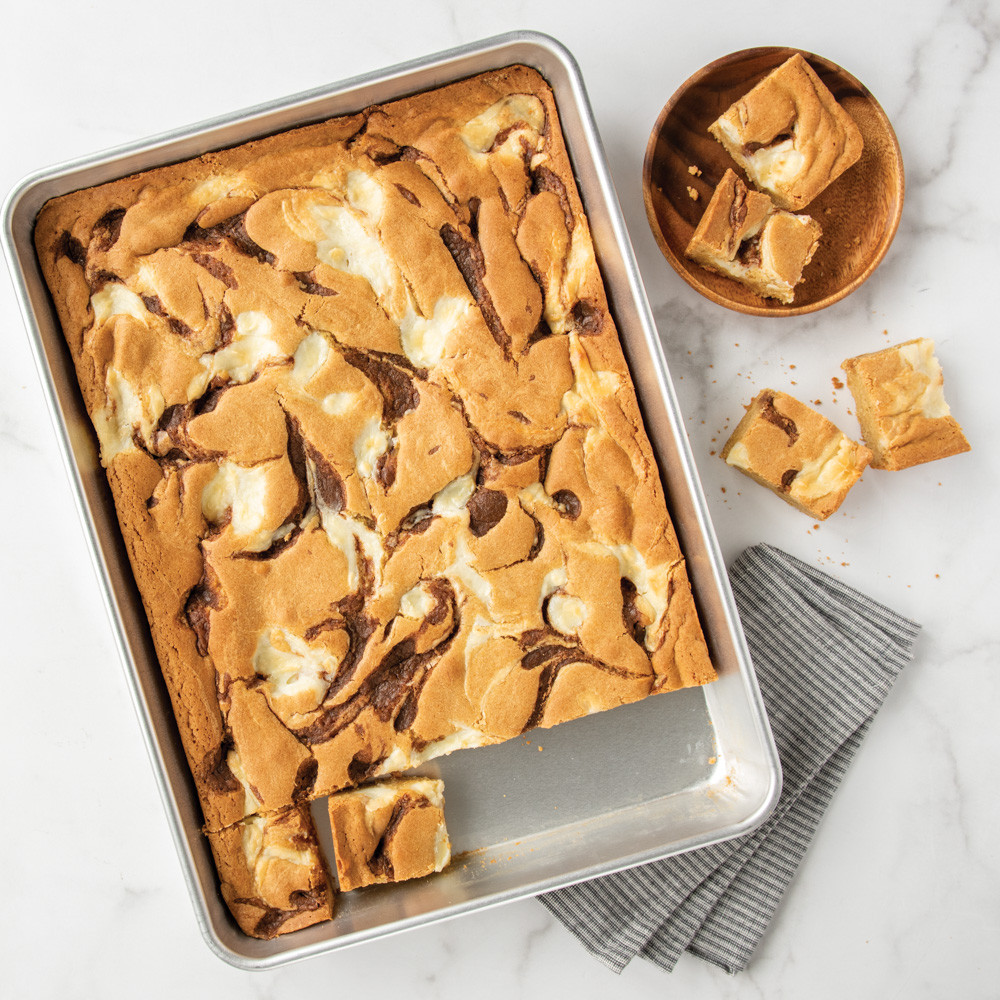 Golden brown chocolate chip blondies in Nordic Ware aluminum high-sided sheet cake pan, cut into squares
