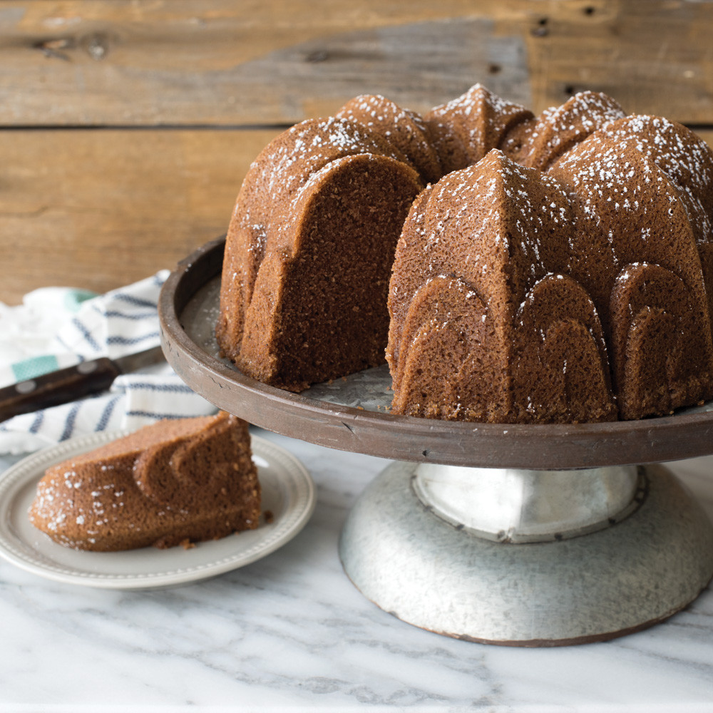 Golden brown spice cake baked in Nordic Ware Fleur-de-Lis bundt pan on ceramic cake stand