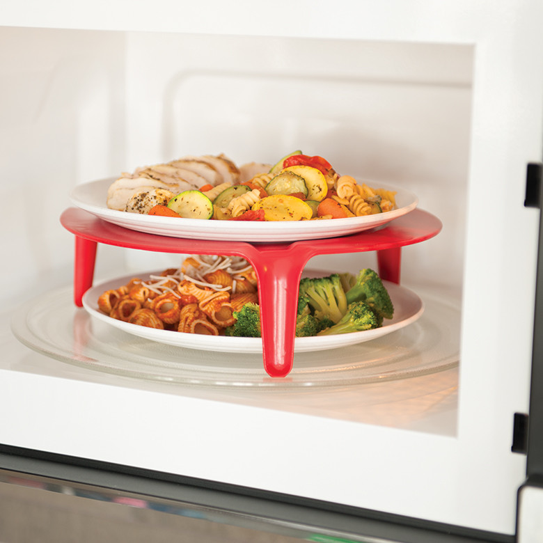 Nordic Ware red microwave plate stacker with pasta and chicken meals on two tiers inside microwave