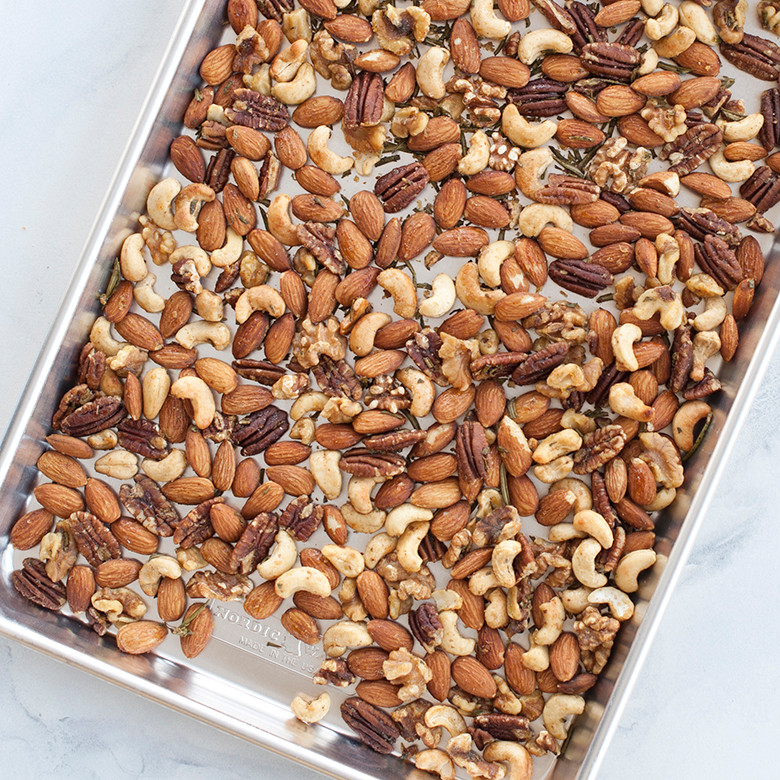Nordic Ware aluminum jelly roll pan filled with golden roasted mixed nuts including almonds, walnuts, and pecans