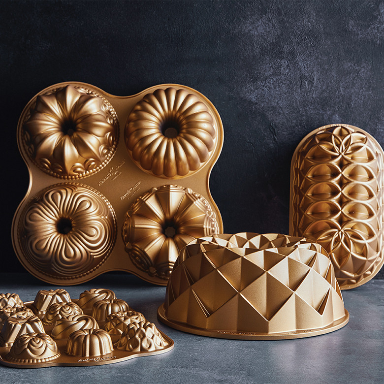 Nordic Ware gold aluminum bundt pan collection featuring four-cavity charms pan, geometric designs, and cathedral bundt pan