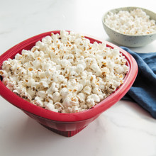 Nordic Ware red Pro Pop Popper bowl filled with freshly popped white and yellow popcorn kernels