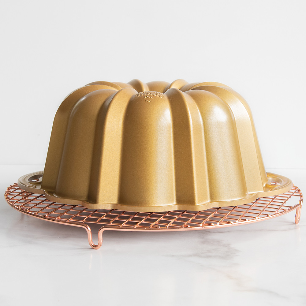 Golden Nordic Ware Anniversary bundt pan inverted on round copper wire cooling grid