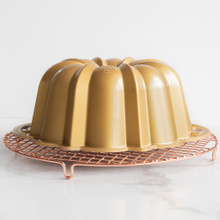 Golden Nordic Ware Anniversary bundt pan inverted on round copper wire cooling grid