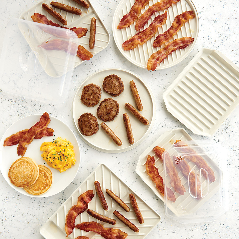 Nordic Ware aluminum slanted bacon trays with ridged surfaces, containing cooked bacon strips and breakfast sausage links