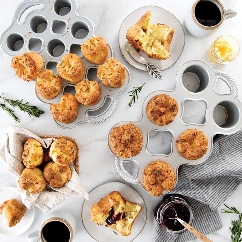 Two Nordic Ware popover pans in different sizes with golden-brown baked popovers, aluminum finish