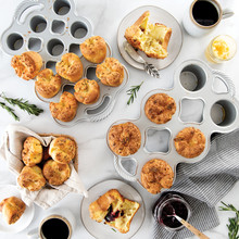 Two Nordic Ware popover pans in different sizes with golden-brown baked popovers, aluminum finish