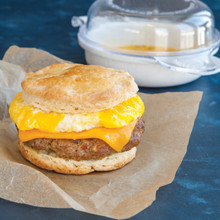 Breakfast sandwich with melted cheese and sausage on biscuit, Nordic Ware Eggs n' Muffin pan visible behind