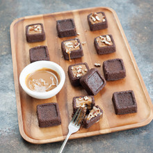Nordic Ware brownie bites pan with baked square brownies, some topped with caramel and chopped nuts