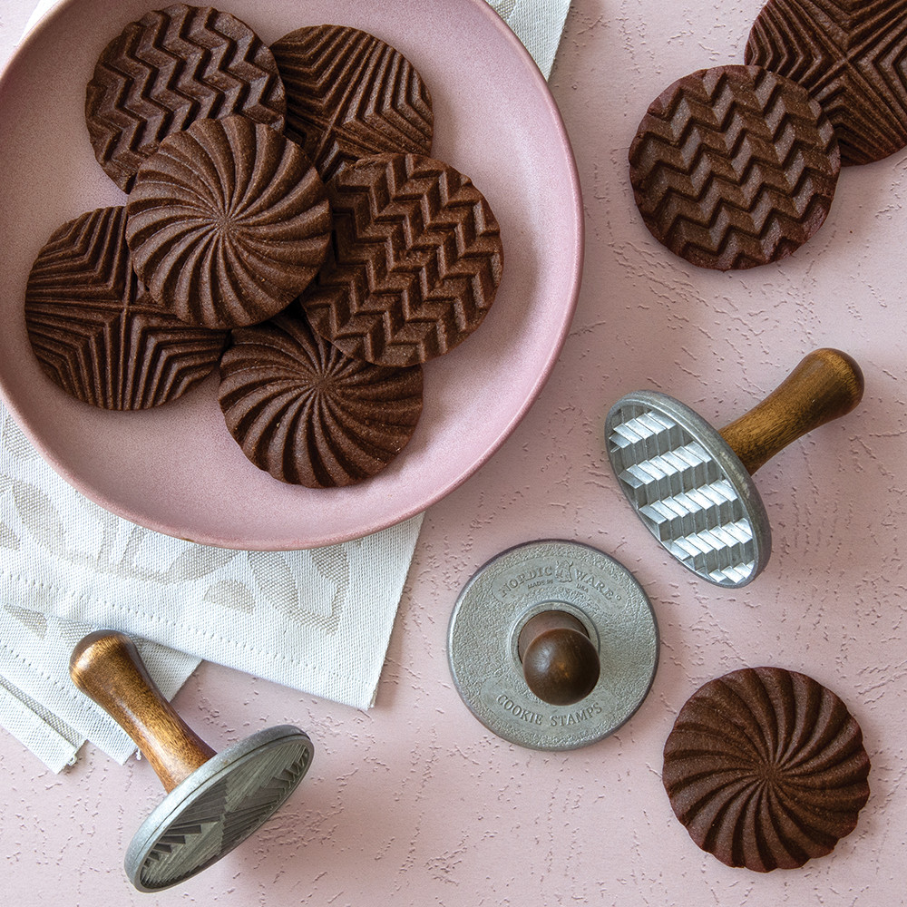 Chocolate cookies with geometric patterns stamped on surface, arranged on white background