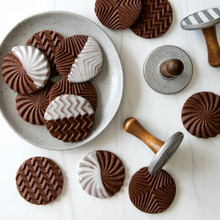Plain and chocolate-dipped cookies with geometric stamped patterns arranged on white plate and marble surface