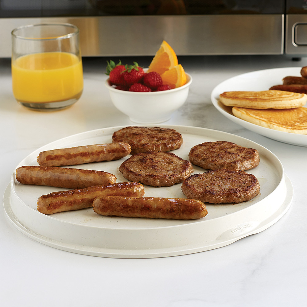 Nordic Ware aluminum two-sided grill pan with cooked sausage patties and links, breakfast spread with pancakes and orange juice