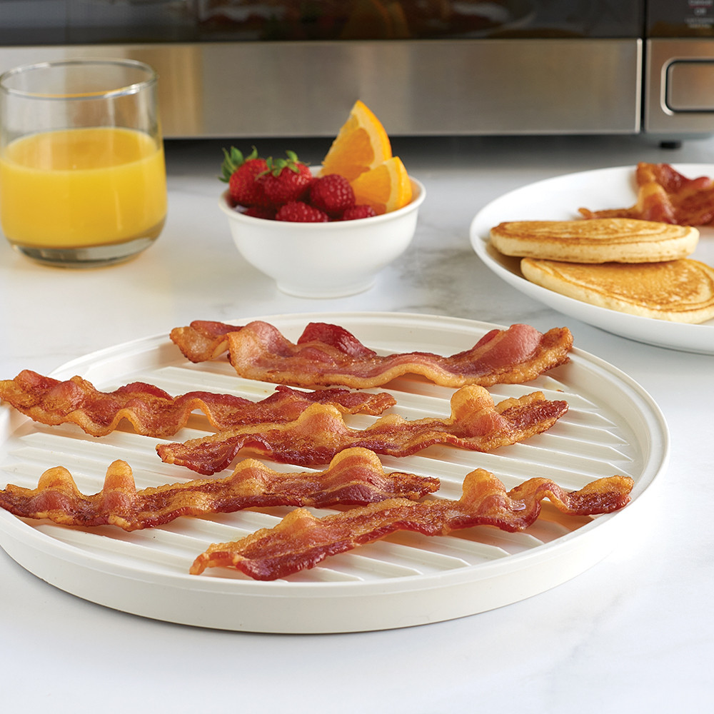 Nordic Ware aluminum two-sided meat grill with cooked bacon strips on ribbed surface, breakfast setting with microwave
