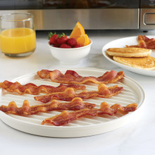 Nordic Ware aluminum two-sided meat grill with cooked bacon strips on ribbed surface, breakfast setting with microwave