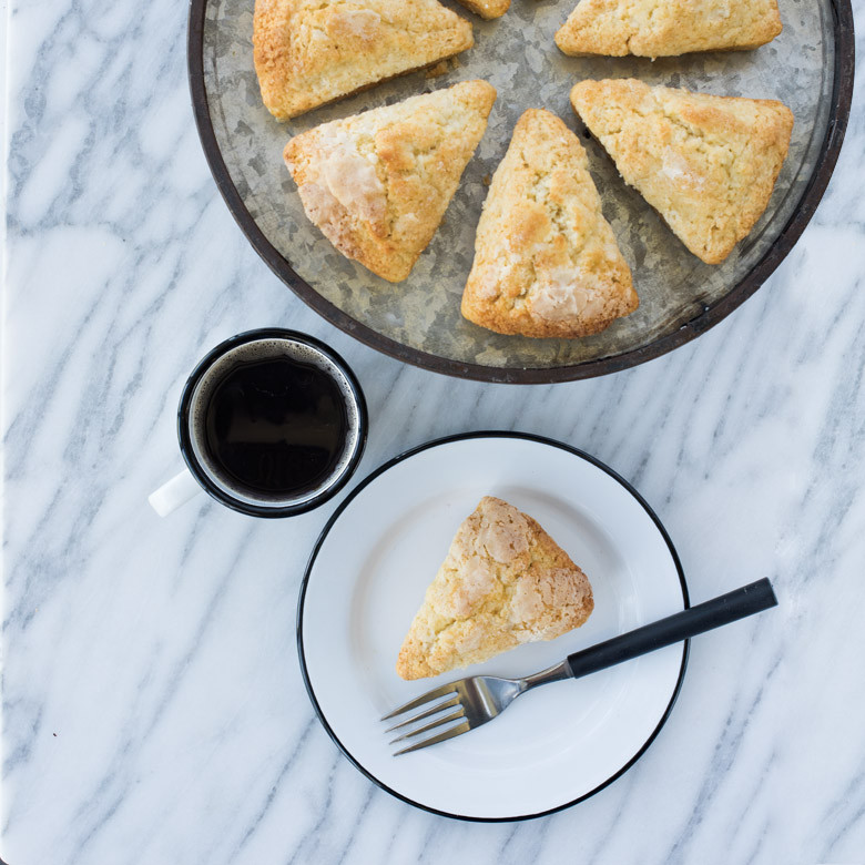 Golden-brown cornbread baked in Nordic Ware Scottish scone pan, cut into 8 triangular wedges, served on white plate with coffee