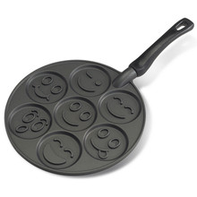 Nordic Ware aluminum pancake pan with seven round wells featuring raised smiley face designs, white background